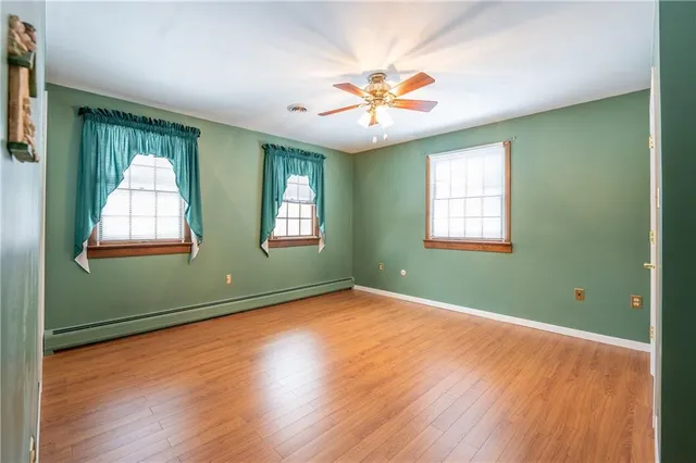 an empty room with wooden floor fan and windows