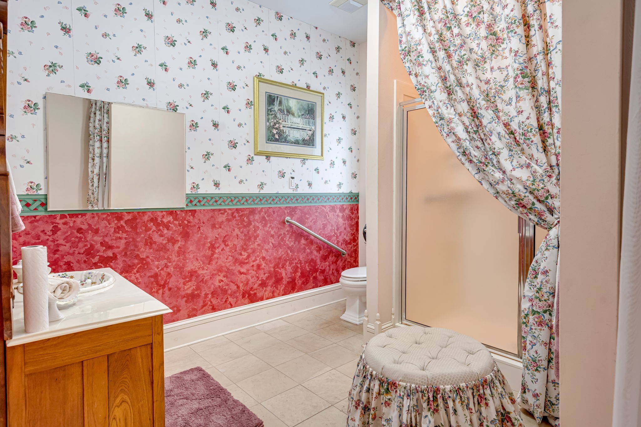 4028 Crosby Cedar Bayou Road Baytown, TX 77521 - Photo 18 of 35 Second full bathroom for Bedroom 2 with tile floors, vanity, walk-in shower (frosted glass), safety grab bar, and ample linen/storage; floral wallcovering adds vintage charm.
