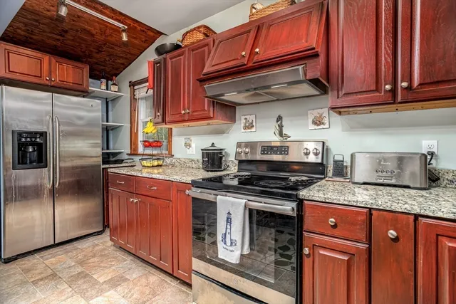 a kitchen with stainless steel appliances granite countertop a stove top oven a refrigerator and cabinets