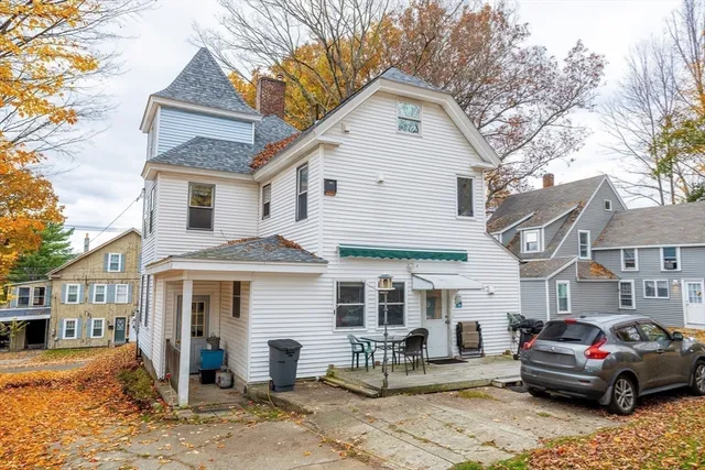 a view of a white house with large windows and lawn chairs