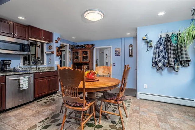 a dining room with stainless steel appliances kitchen island granite countertop a dining table chairs and a refrigerator