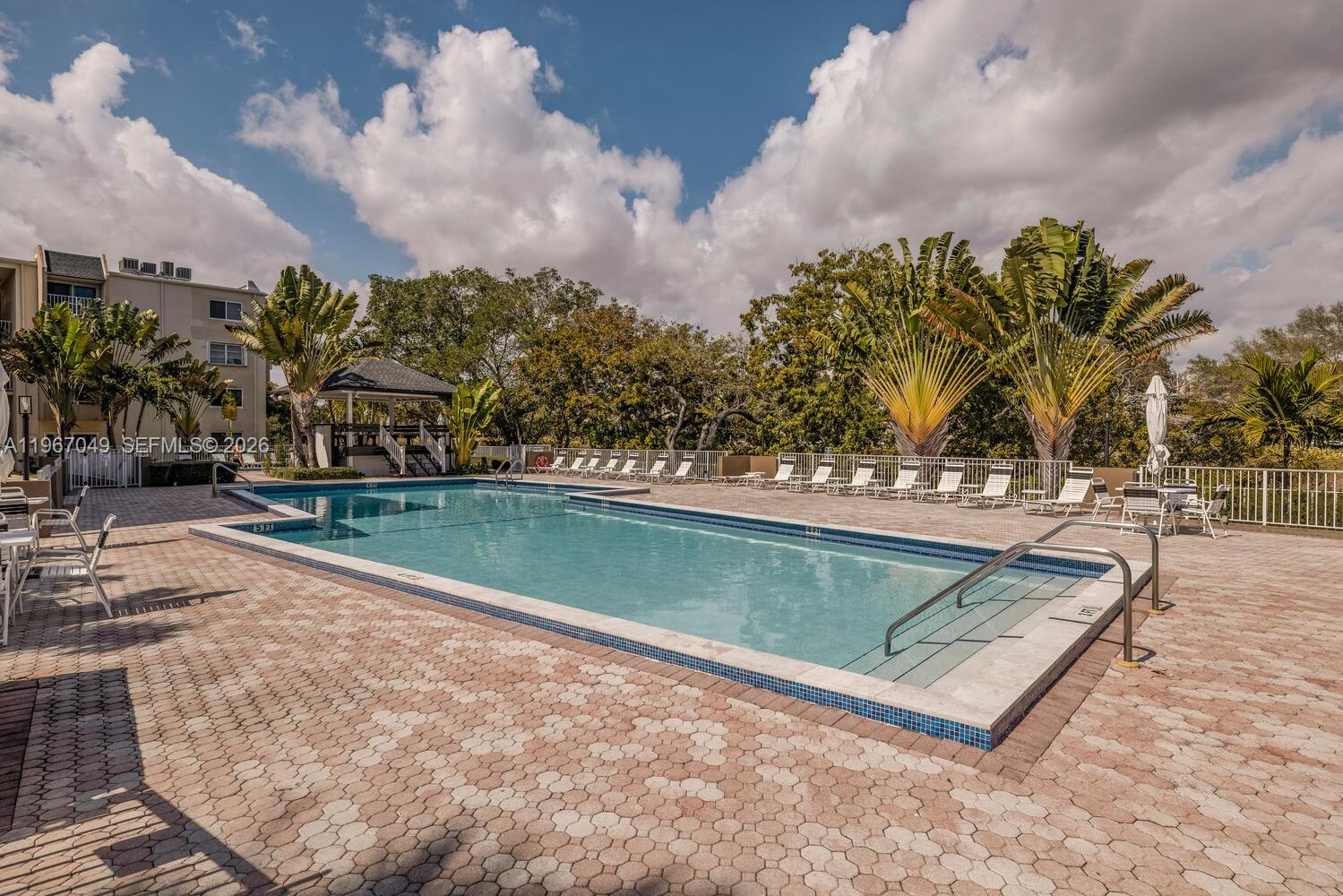 7785 Southwest 86th Street, Unit E119 Miami, FL 33143 - Photo 24 of 33 a view of a swimming pool with a bench and trees in the background