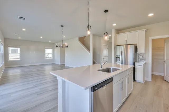 a kitchen with a sink a center island wooden floor and a ceiling fan