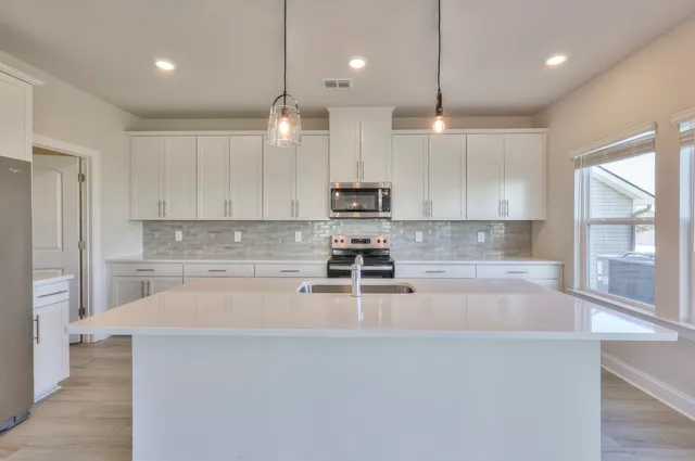 a large kitchen with stainless steel appliances granite countertop a sink a stove and a refrigerator