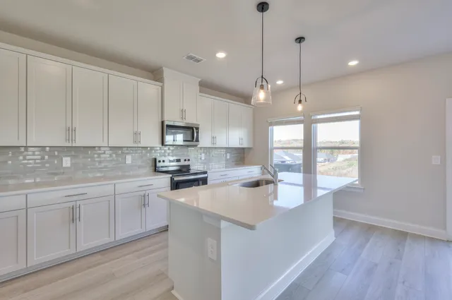 a large kitchen with stainless steel appliances granite countertop a sink a stove and a wooden floors