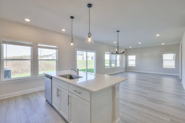 a kitchen with granite countertop a stove a sink a window and wooden floor