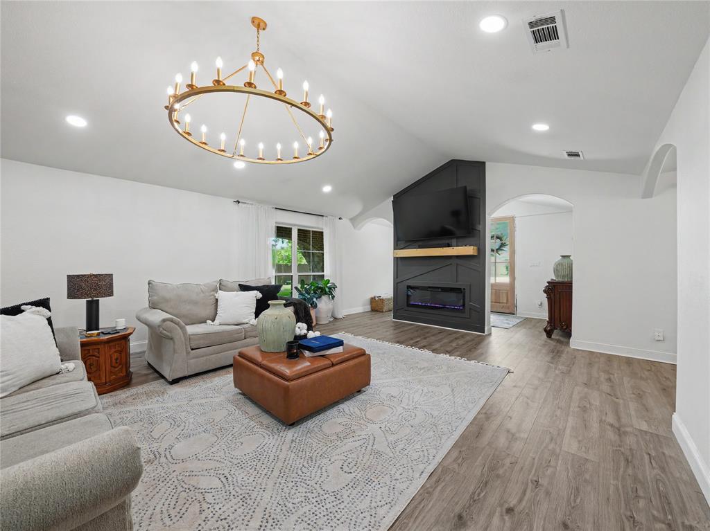 6701 Nauert Road Forest Hill, TX 76140 - Photo 6 of 40 Spacious living area featuring wood-finish flooring, a modern electric fireplace with a wood mantel, and multiple recessed lights