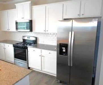 a kitchen with stainless steel appliances granite countertop a refrigerator a stove and a sink with cabinets