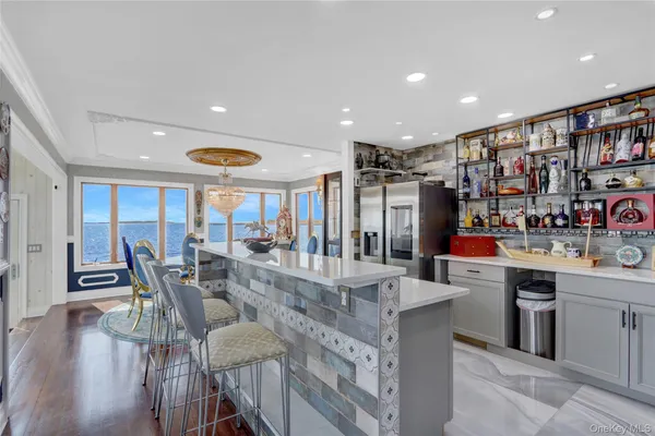 a kitchen with stainless steel appliances kitchen island granite countertop a table chairs and a refrigerator