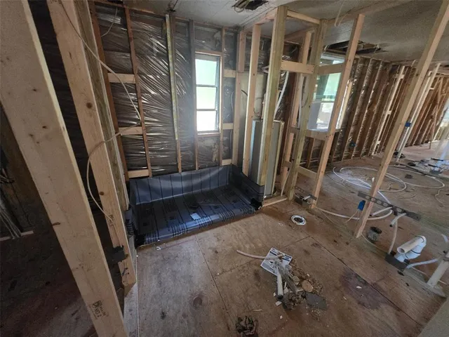 a view of an empty room with wooden floor and windows