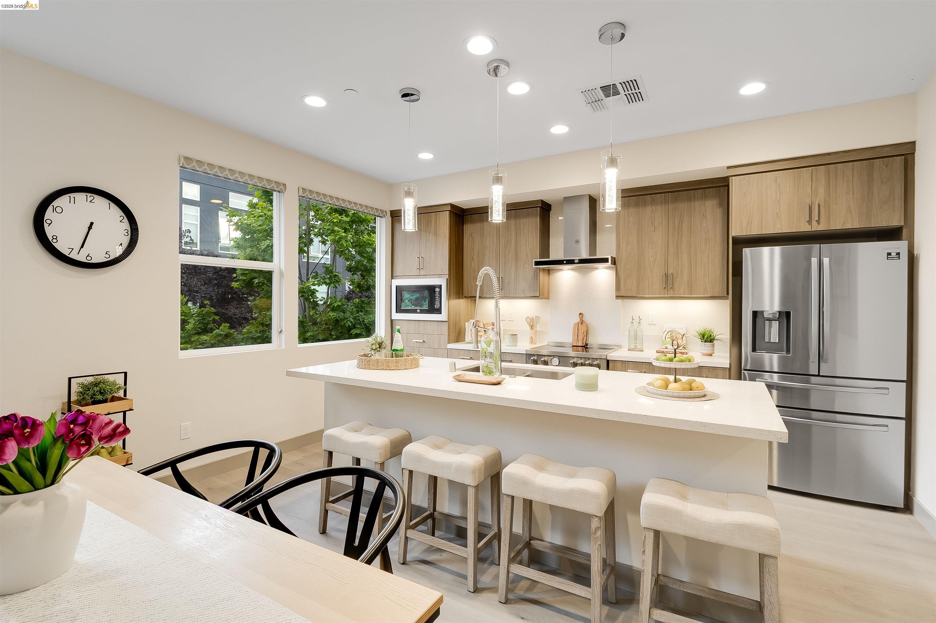 1357 Pullman Way Oakland, CA 94607 - Photo 10 of 37 Modern kitchen featuring a white countertop island, stainless steel appliances, wood-finish cabinetry, recessed lighting, and pendant lights