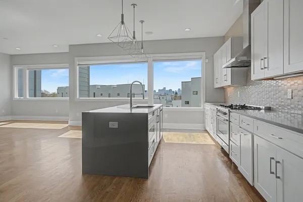 a kitchen with stainless steel appliances granite countertop a sink a stove and a wooden floors