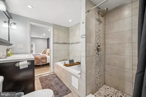 a bathroom with a bathtub shower sink vanity and toilet