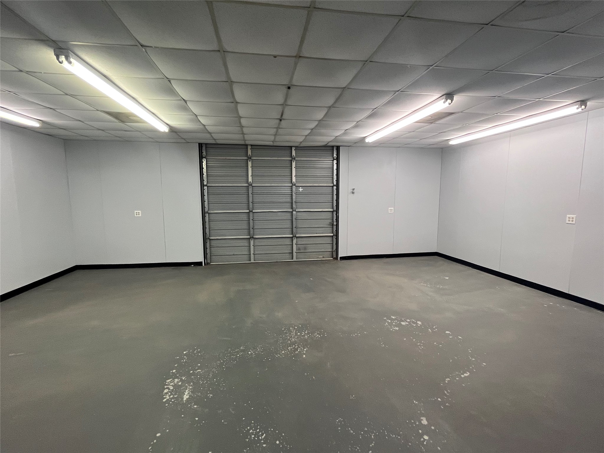 741 Knobbs Road McDade, TX 78650 - Photo 33 of 38 A spacious, well-lit garage featuring a roll-up door, ideal for storage or vehicle accommodation.