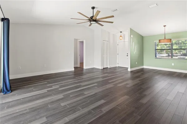 an empty room with wooden floor ceiling fan and window
