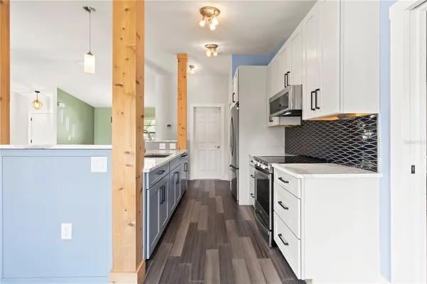 a kitchen with a sink a stove top oven and wooden floor