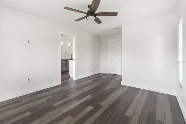 a view of a room with wooden floor and a ceiling fan