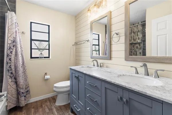 a bathroom with a granite countertop sink toilet and mirror