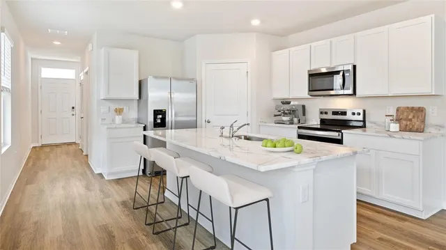 a kitchen with stainless steel appliances a sink a stove a refrigerator cabinets and a counter top space