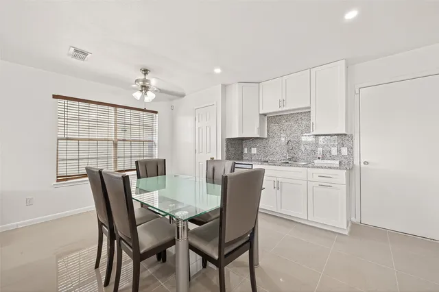 a kitchen with stainless steel appliances granite countertop a stove a sink a microwave a dining table and chairs