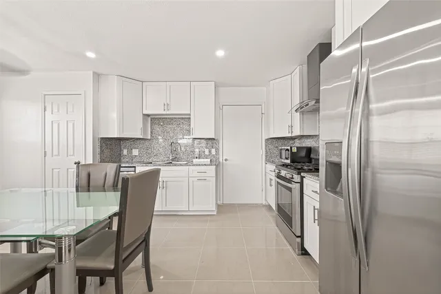 a kitchen with white cabinets and appliances
