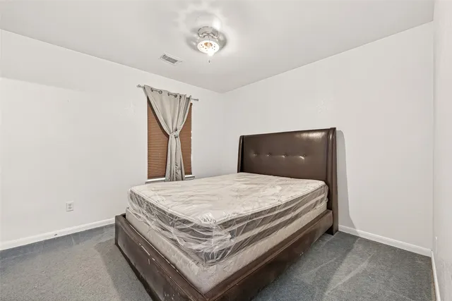 a bedroom with a large bed and chandelier fan