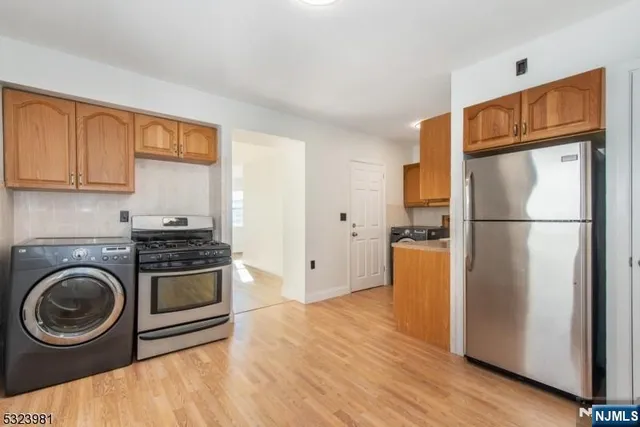 a kitchen with a refrigerator a stove top oven and wooden floor