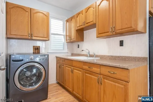 a kitchen with stainless steel appliances granite countertop a sink a washer and dryer with wooden cabinets