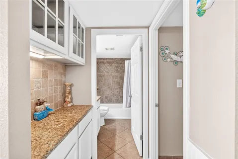 a bathroom with a granite countertop bathtub sink vanity mirror and toilet