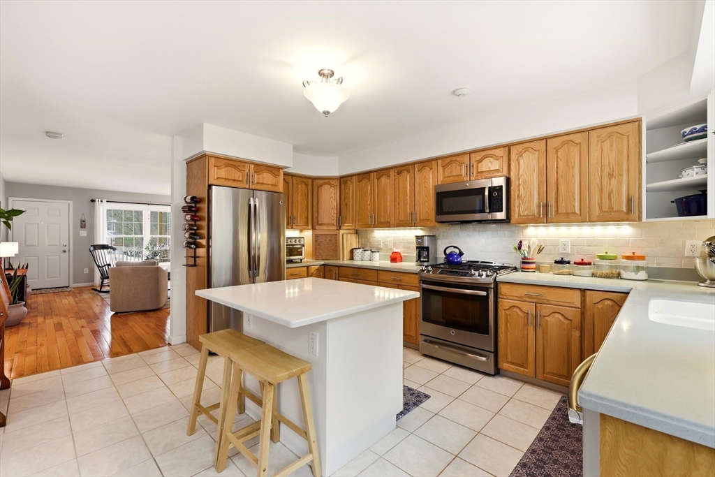 175 Leonard Street, Unit 2 Raynham, MA 02767 - Photo 6 of 27 a kitchen with stainless steel appliances granite countertop a refrigerator a stove top oven a sink dishwasher and white cabinets with wooden floor