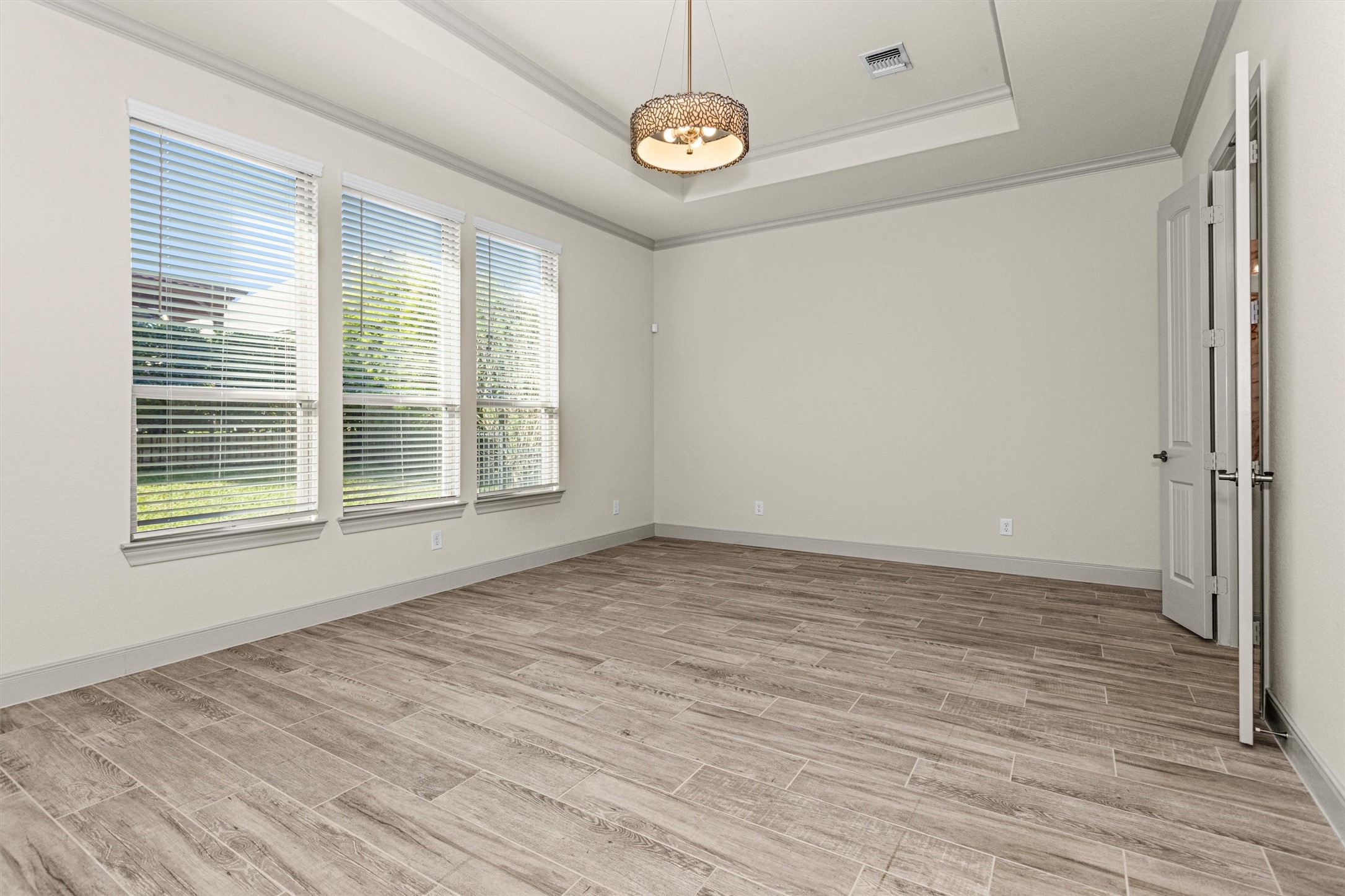 209 Fox Trotter Spring, TX 77382 - Photo 14 of 33 Discover the owners' suite, featuring a stunning tray ceiling, elegant designer lighting, and expansive windows with serene backyard views.