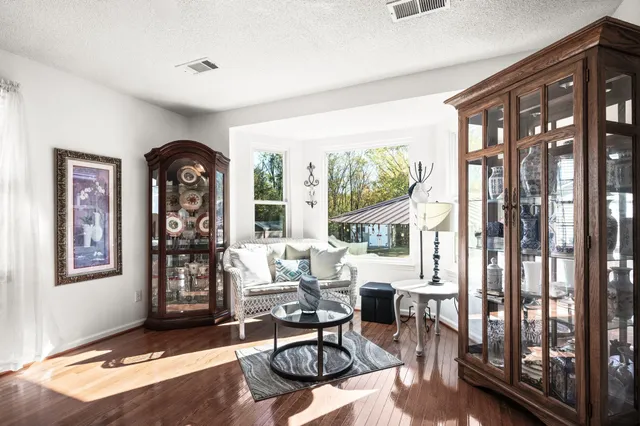 a living room with furniture large window and wooden floor