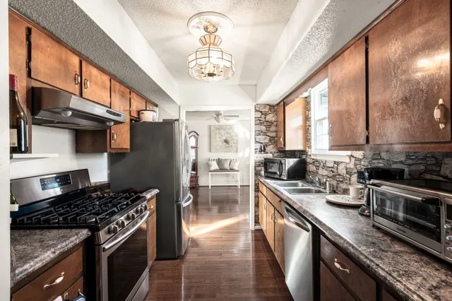 a kitchen with stainless steel appliances granite countertop a stove top oven a sink dishwasher a stove and a refrigerator