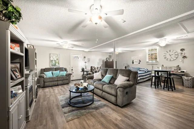 a living room with furniture kitchen view and a wooden floor