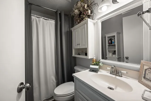 a bathroom with a sink a toilet a mirror and shower