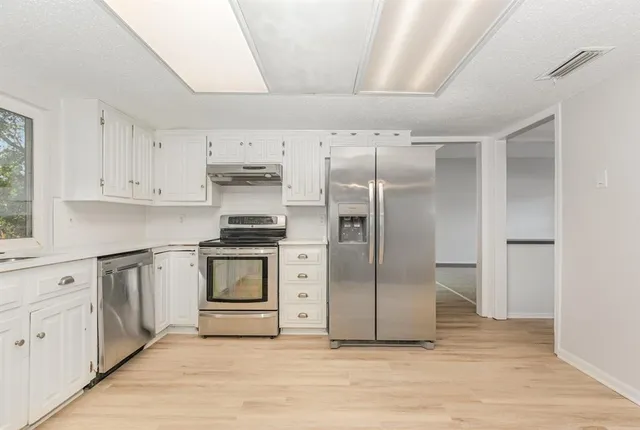 a kitchen with granite countertop white cabinets and stainless steel appliances