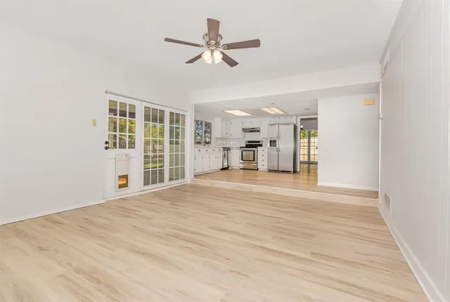 a view of empty room with wooden floor and a ceiling fan