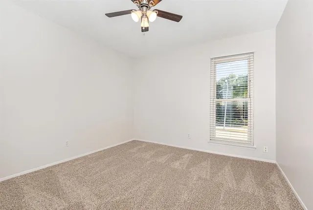 an empty room with a chandelier fan and windows
