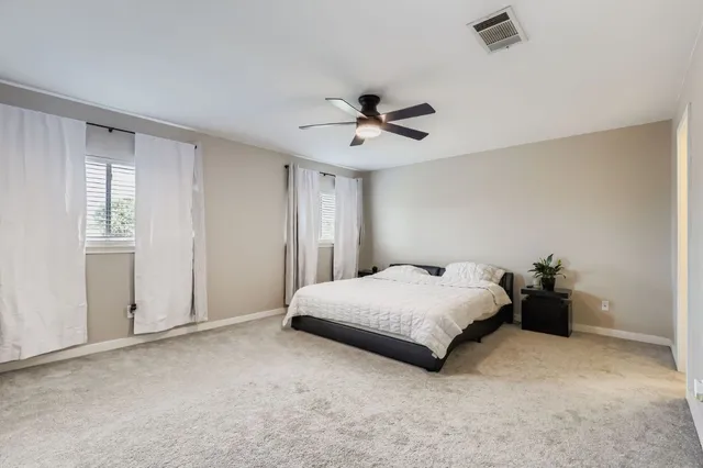 a spacious bedroom with a bed and a ceiling fan