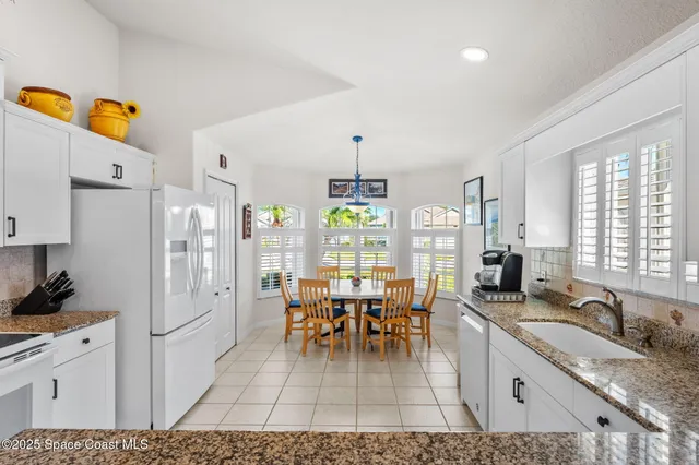 a living room with stainless steel appliances kitchen island granite countertop furniture and a chandelier