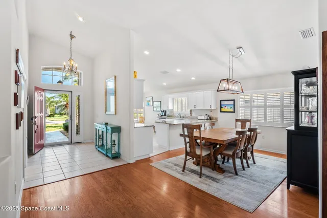 a view of a dining room and livingroom with furniture wooden floor a chandelier