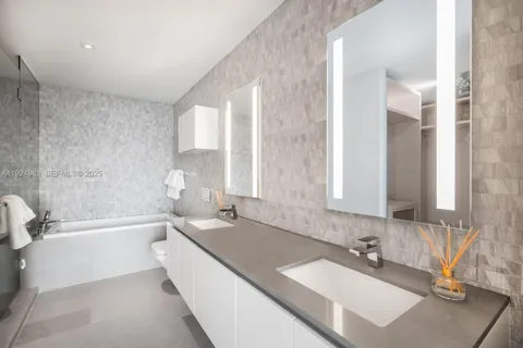 a bathroom with a granite countertop sink and a bathtub