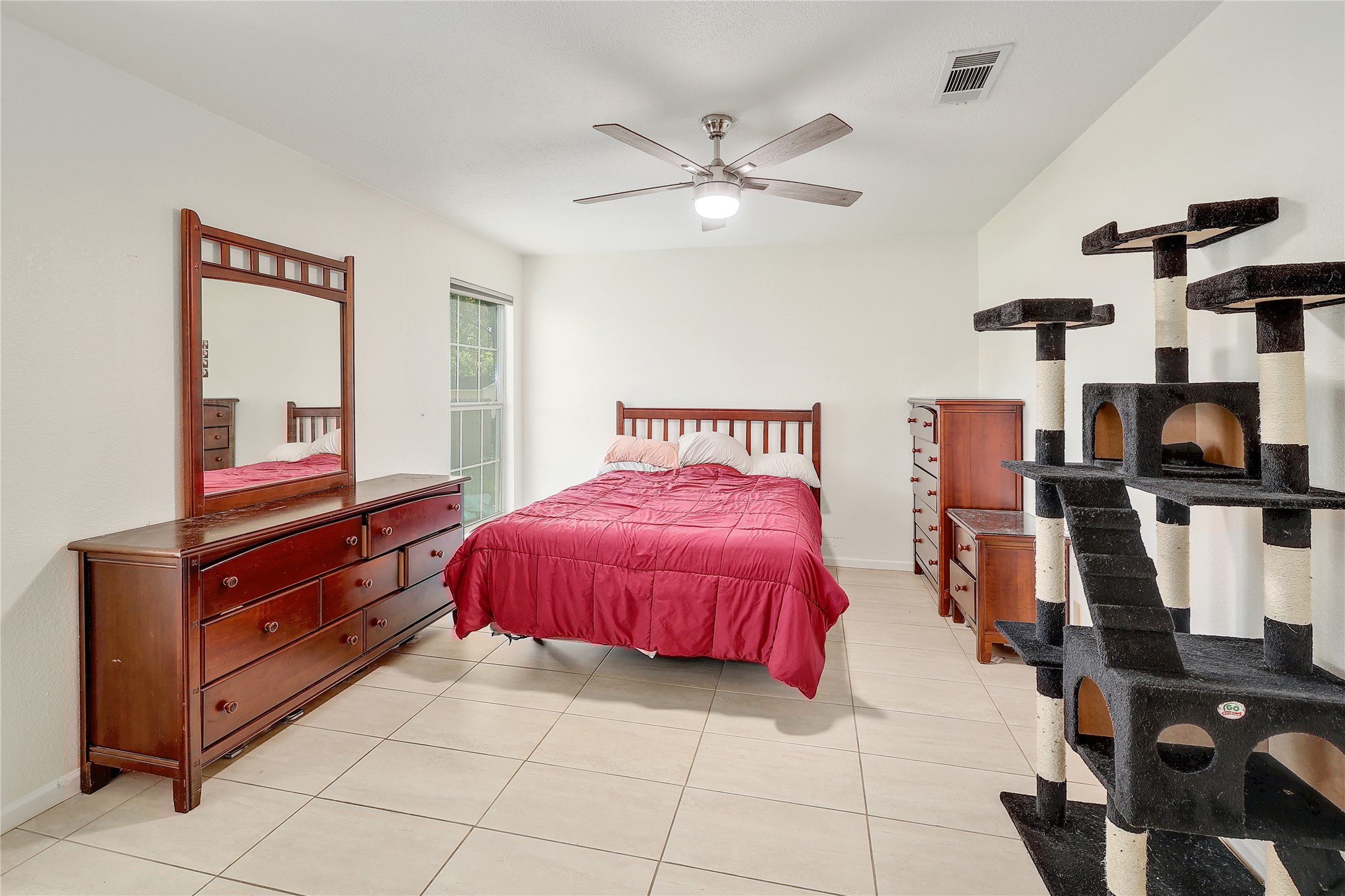 9906 Parliament House Road Austin, TX 78729 - Photo 21 of 33 Tiled flooring and a tall window bring simple elegance to this bedroom.