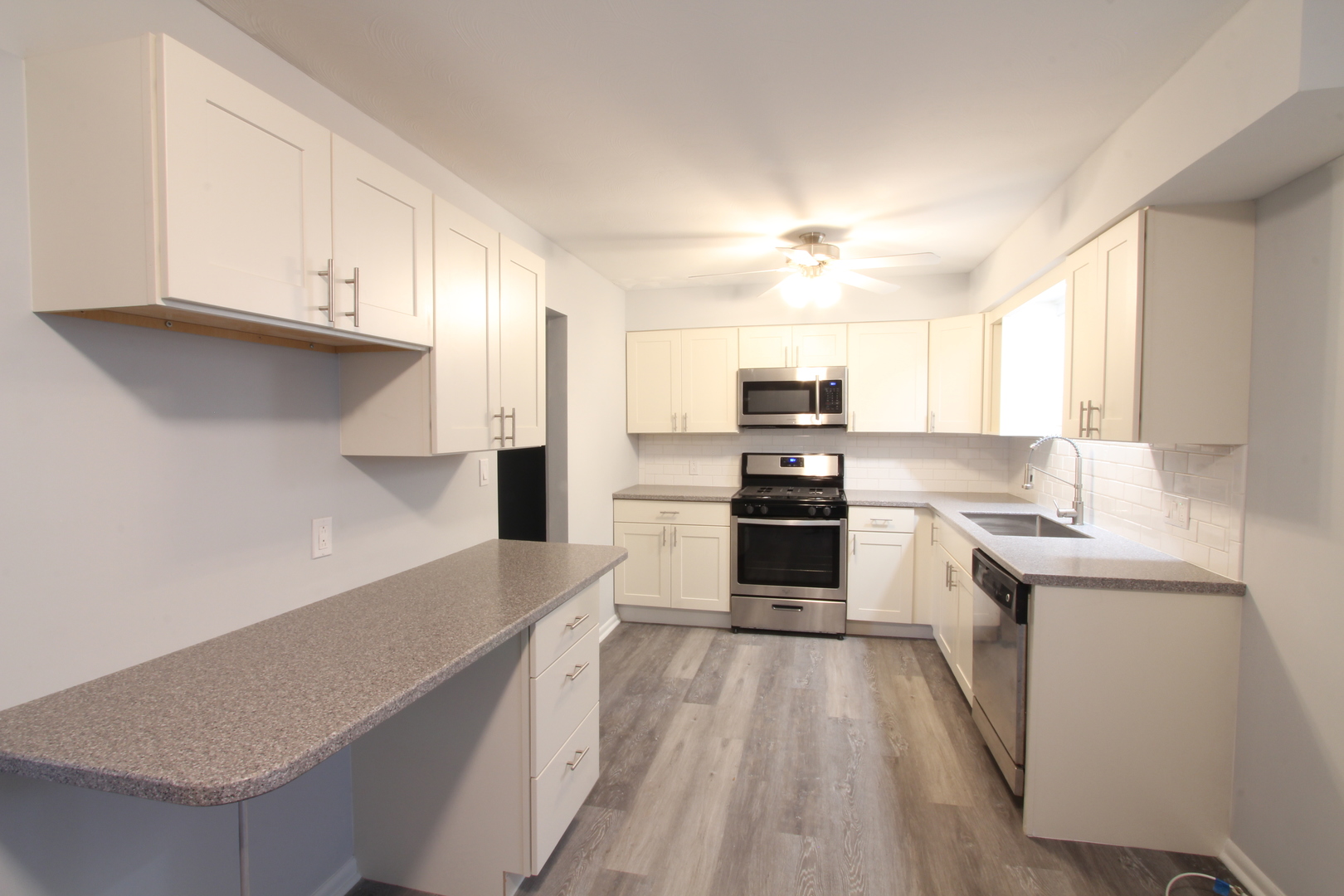 703 Sheridan Road Normal, IL 61761 - Photo 5 of 15 a kitchen with stainless steel appliances a stove top oven a sink dishwasher and a refrigerator with wooden floor