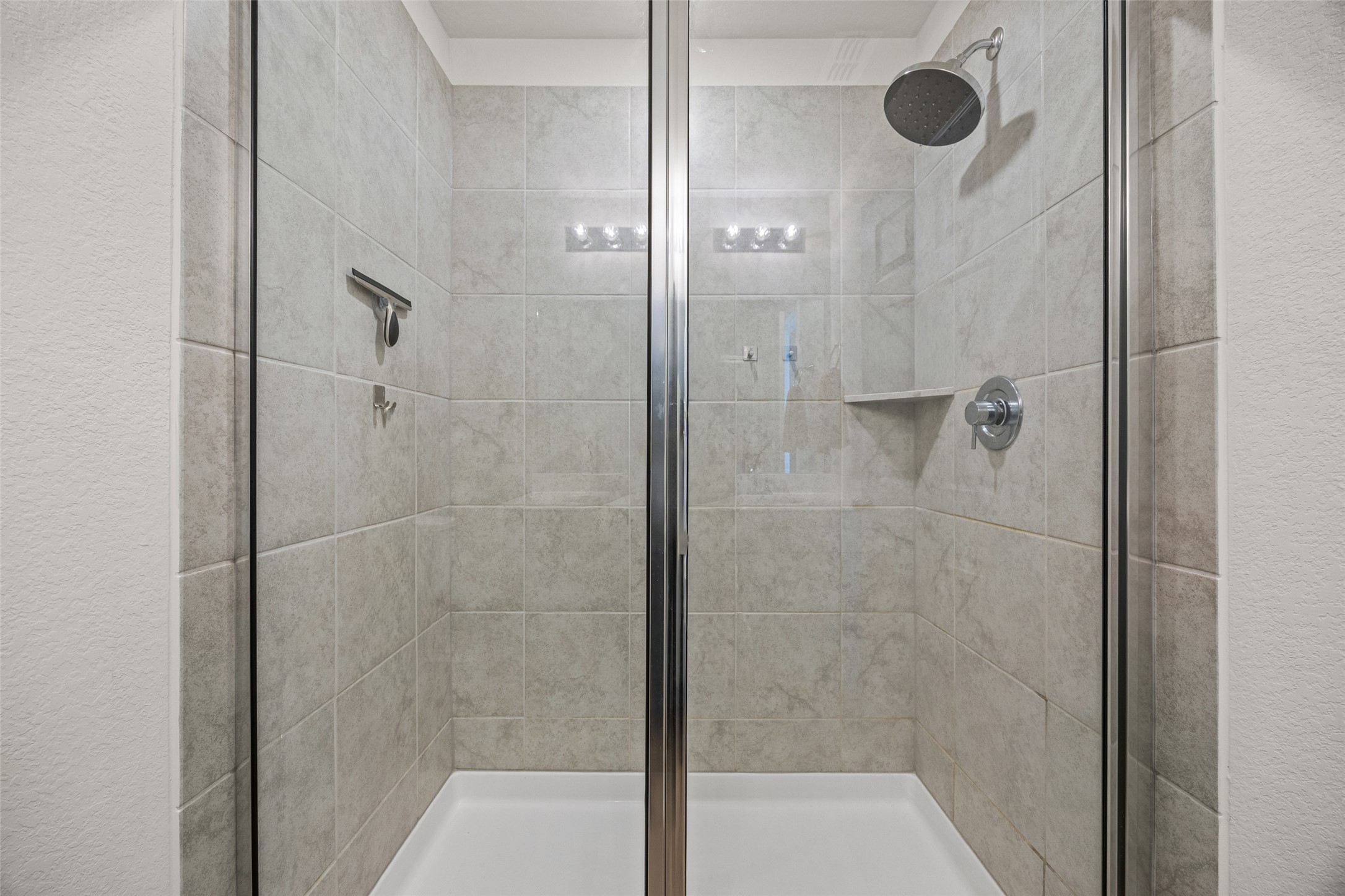 208 Orange Road Buda, TX 78610 - Photo 16 of 31 A well-appointed shower stall features tiled walls and a glass enclosure.