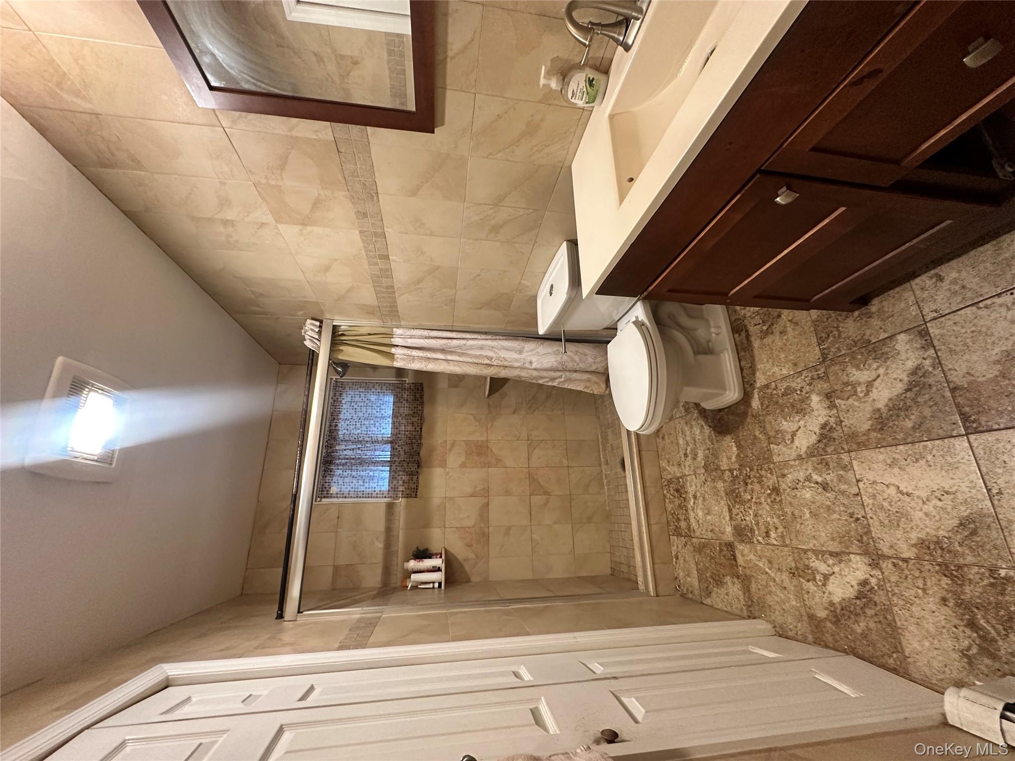 16 Spring Street Roosevelt, NY 11575 - Photo 14 of 19 a bathroom with a sink a toilet a mirror and shower