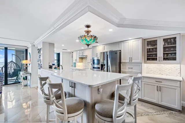 a kitchen with stainless steel appliances kitchen island granite countertop a dining table chairs and a refrigerator
