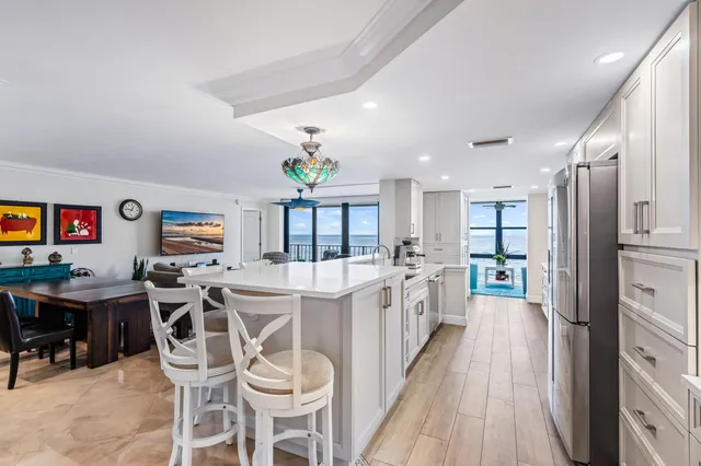 a kitchen with stainless steel appliances kitchen island granite countertop a table chairs and a refrigerator
