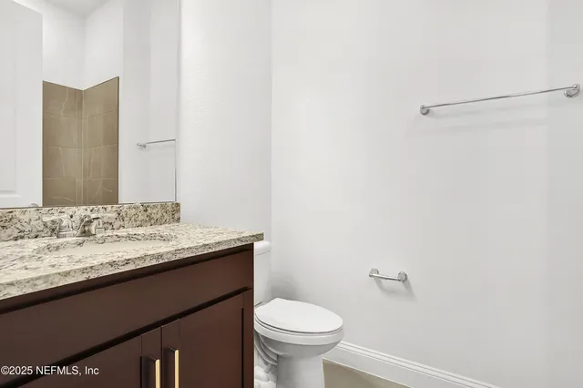 a bathroom with a granite countertop sink toilet and a mirror