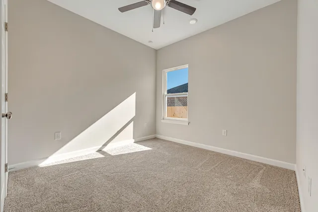 an empty room with windows and chandelier fan